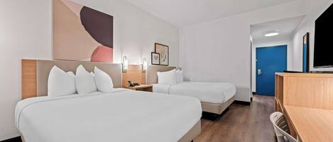 Ett hotellrum med två sängar, ett skrivbord, en stol och en TV.