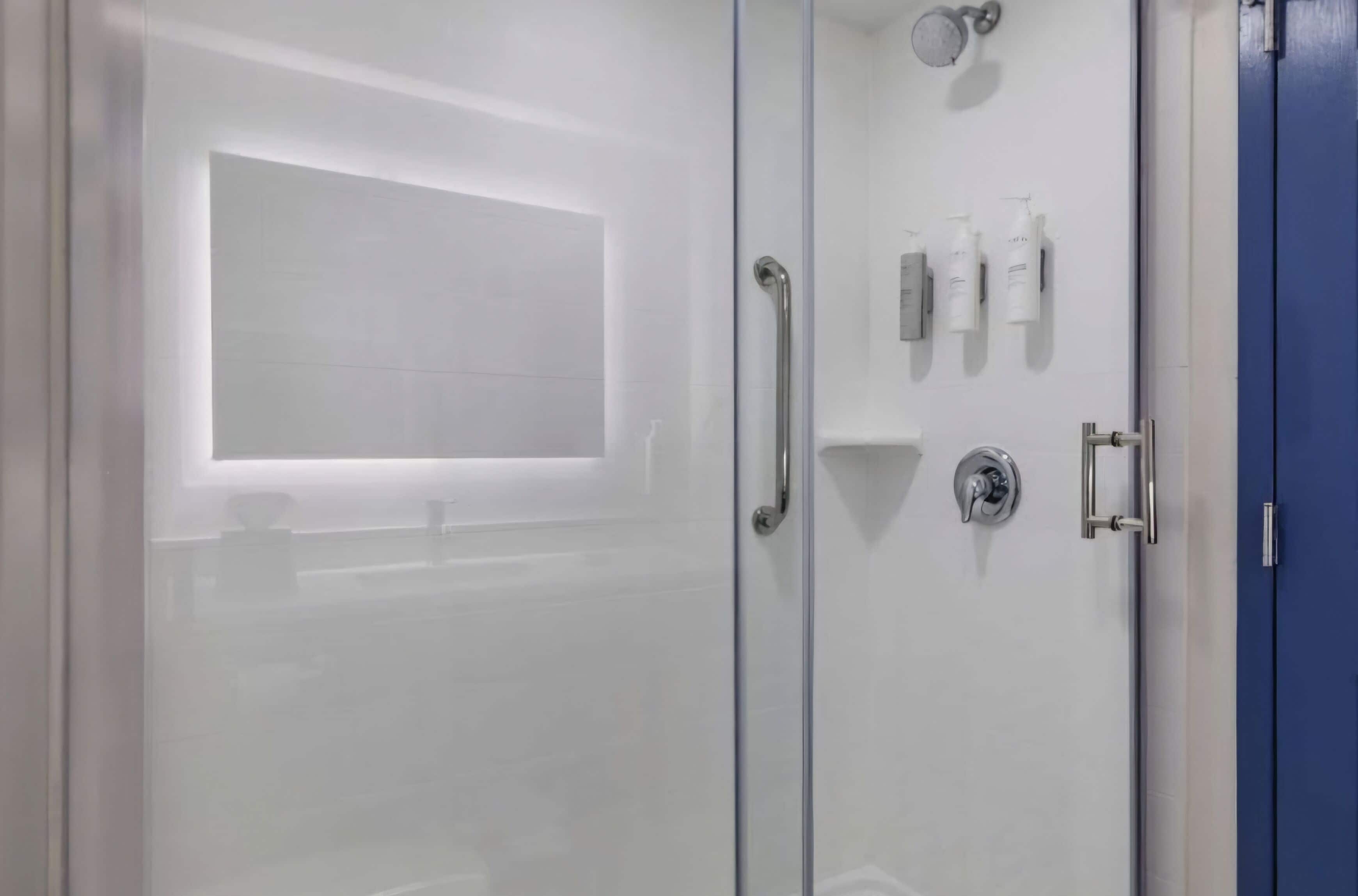 A modern bathroom with a glass shower enclosure, a white sink, and toiletries on the wall.