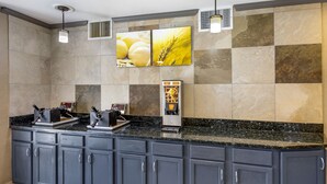 A modern kitchen with grey cabinets, a black granite countertop, and a coffee machine. - Comfort Suites Denver Tech Center (Englewood)
