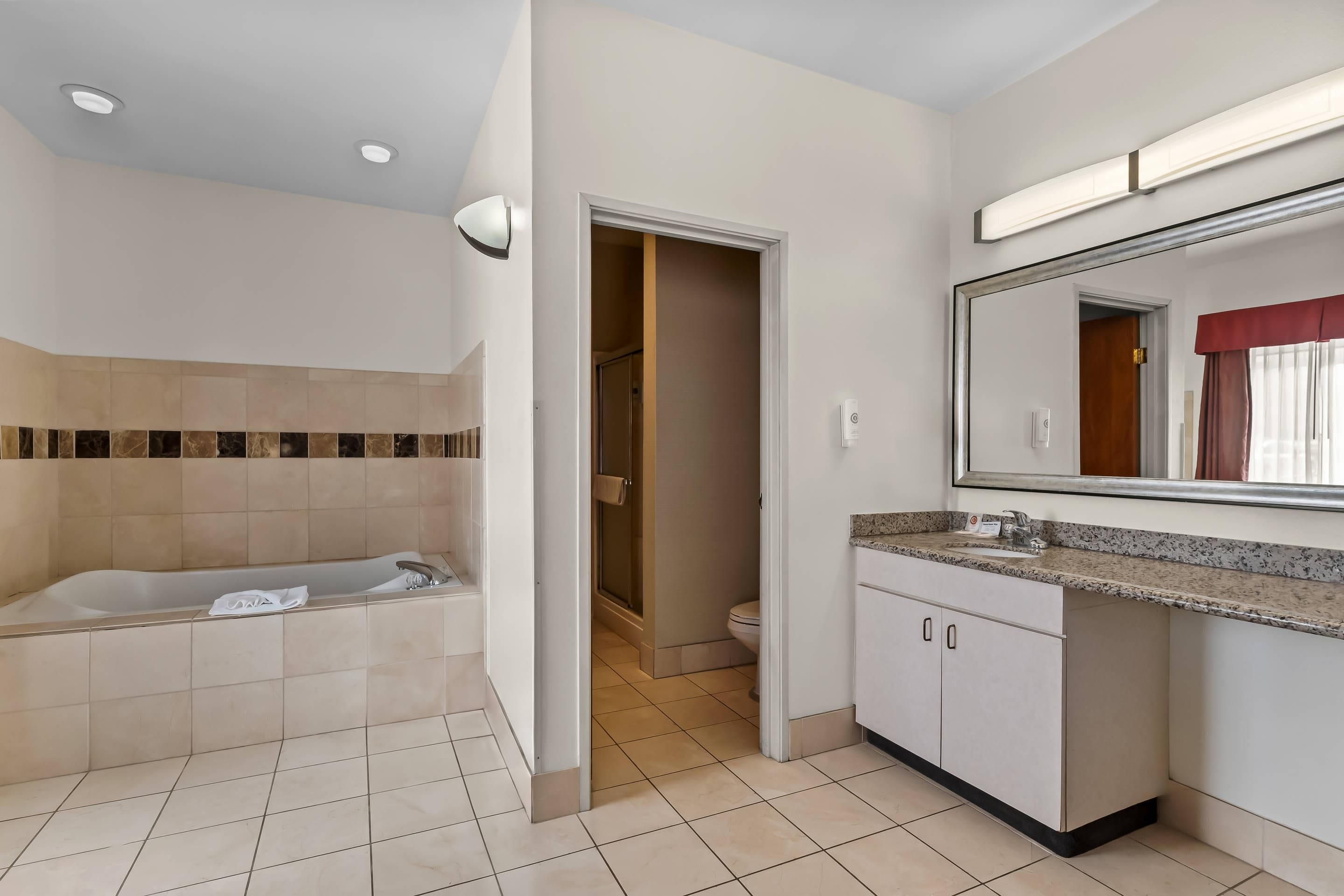 Une salle de bain moderne équipée d’une baignoire, de toilettes et d’un meuble-lavabo avec un miroir.