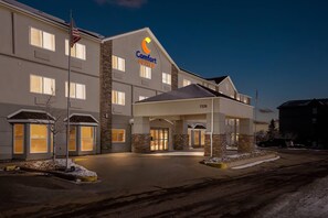 A Comfort Suites hotel with a modern design, featuring a prominent American flag, a well-lit entrance, and a number '7374' on the building. - Comfort Suites Denver Tech Center (Englewood)