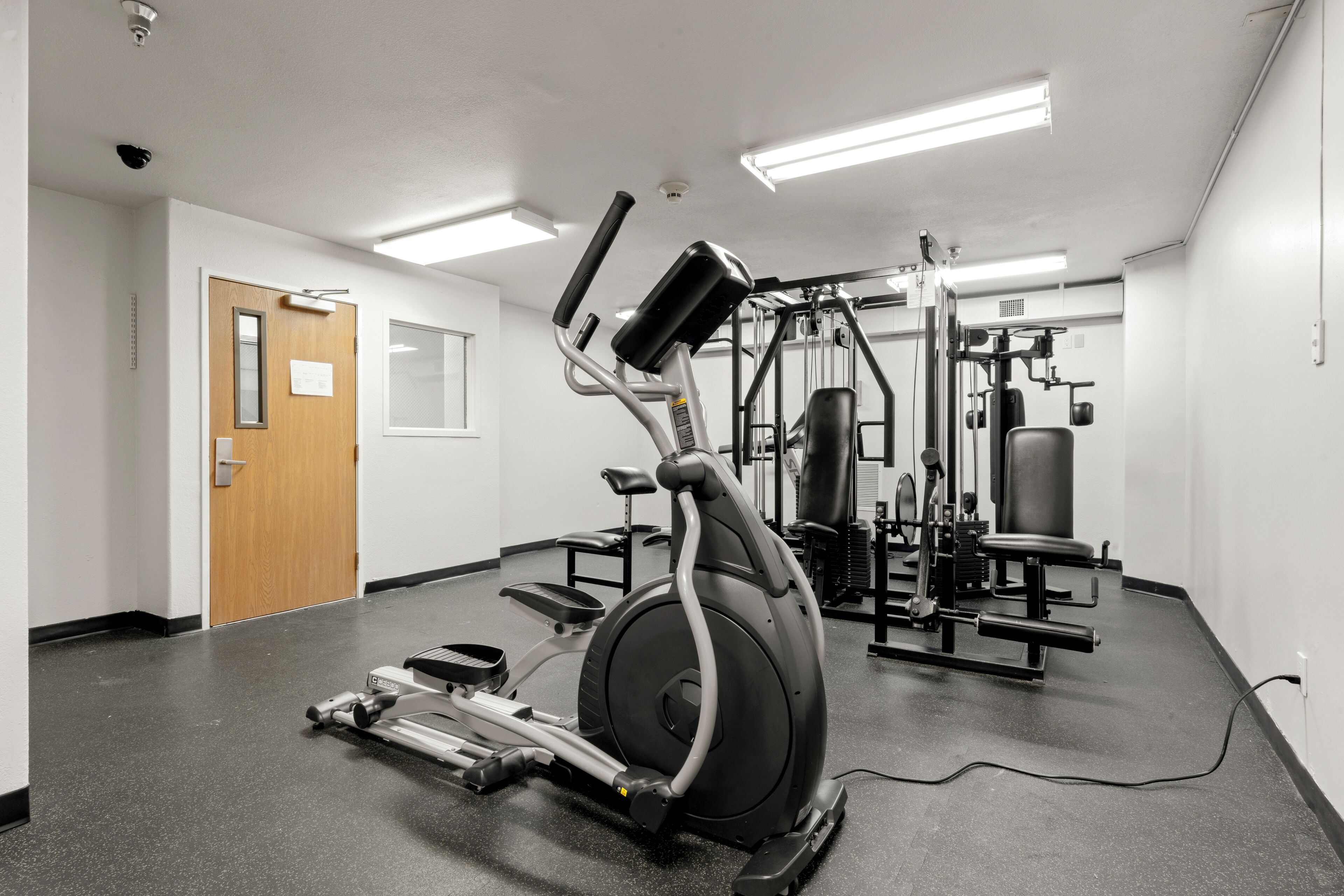 A gym with cardio equipment, weight machines, and a door.