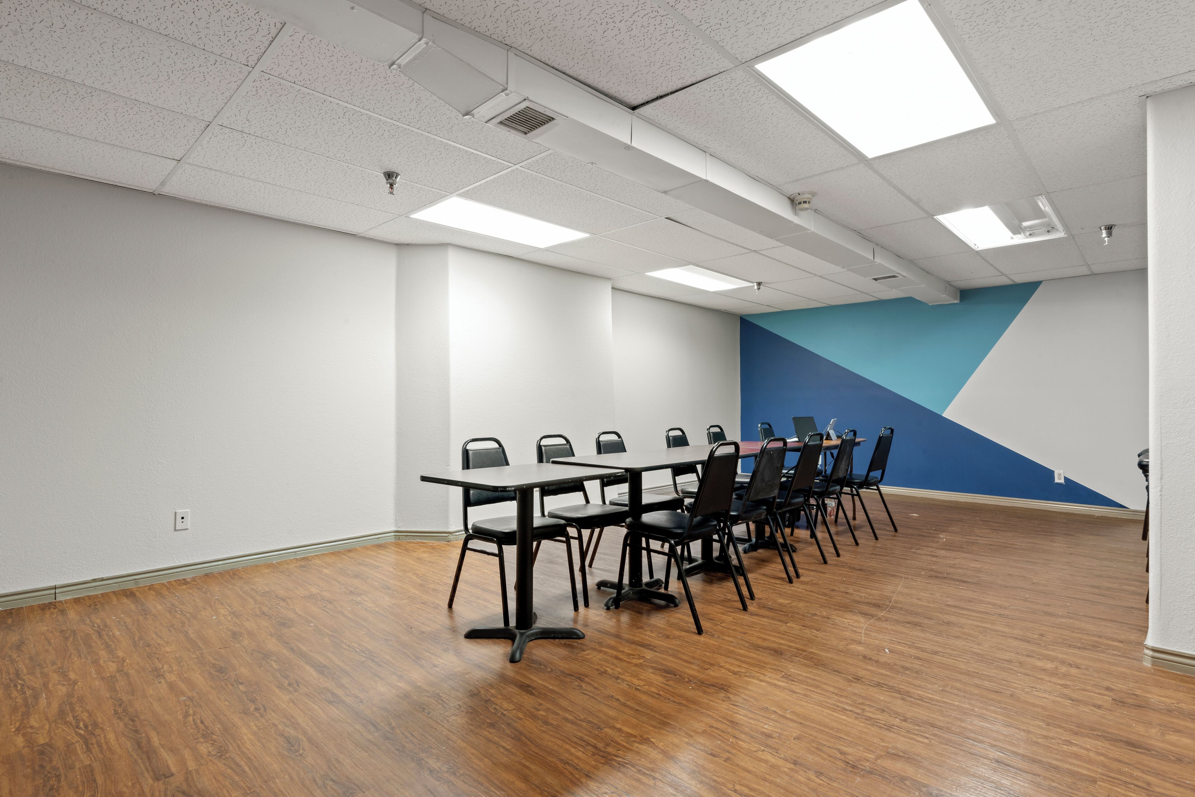A conference room with a long table and chairs, white walls, and a blue accent wall.