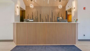A reception desk with vertical wooden slats, a flat surface, and two illuminated wall sconces. - Days Inn by Wyndham Thornton (Thornton)