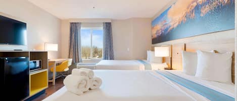 Habitación de hotel con una cama grande, un escritorio, un televisor y un cuadro de un paisaje montañoso.