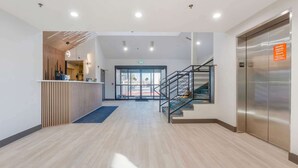 A modern reception area with a wooden partition, a reception desk, a staircase, and an elevator. - Days Inn by Wyndham Thornton (Thornton)