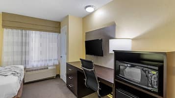 Habitación de hotel con cama, escritorio con computadora, televisión y microondas.