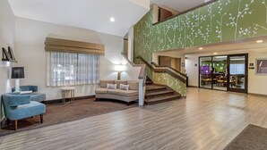 A spacious lobby with a staircase, a seating area with a sofa and armchairs, and a dining area in the background. - Sleep Inn Denver Tech Center (Greenwood Village)