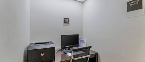 Pequeño espacio de oficina con una impresora Dell, una computadora y una silla. Hay un letrero que indica un escritorio con útiles de oficina adicionales y otro letrero para acceso a internet inalámbrico de alta velocidad.