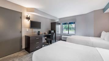 A hotel room with a bed, a desk, a chair, a television, and a window with a view of the outdoors.
