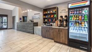 Un espace d’accueil comprenant un comptoir, une machine à café, une étagère à collations et un réfrigérateur pour les boissons.