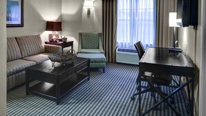 A hotel room with a sofa, a small table, a chair, a desk, and a television. - Holiday Inn Express & Suites Atlanta Buckhead by IHG (Atlanta)