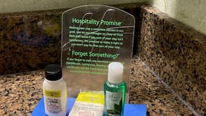 Toiletries on a blue mat with a sign about hospitality promise in the background. - Holiday Inn Express & Suites Atlanta Buckhead by IHG (Atlanta)