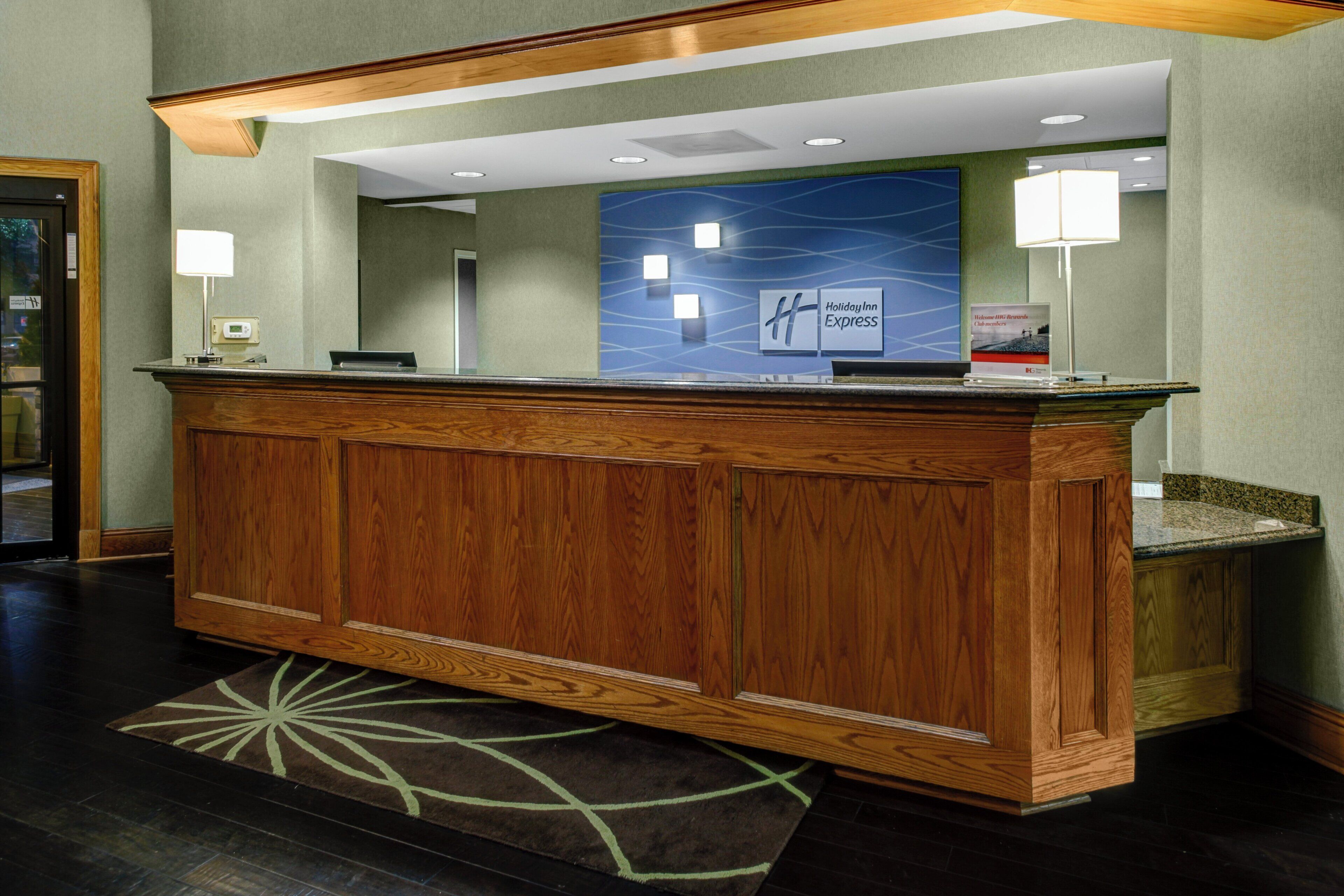 A reception desk with a wooden finish, a blue wall with a wave pattern, and a sign for Holiday Inn Express.