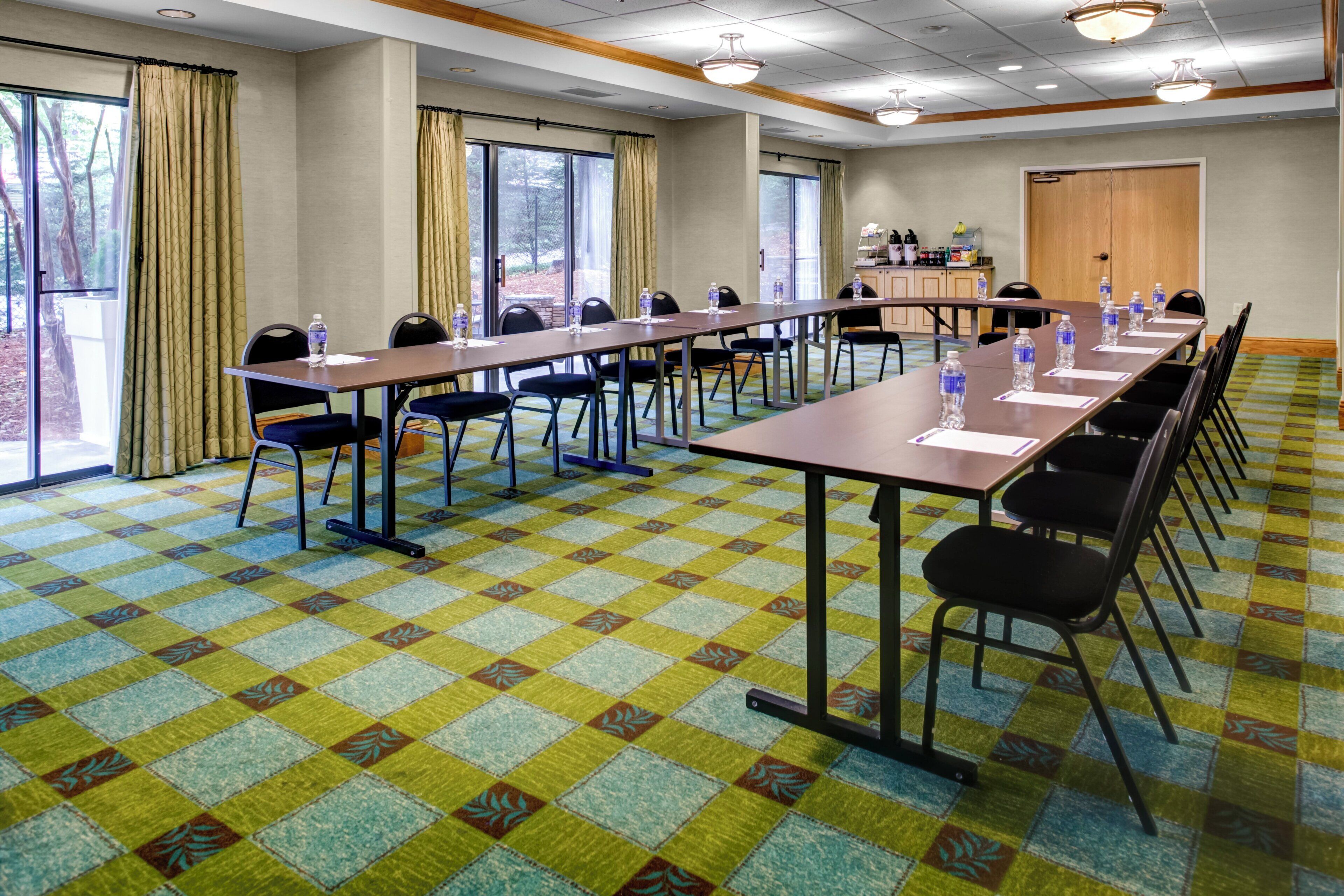 A conference room with a long table, chairs, and a patterned carpet.