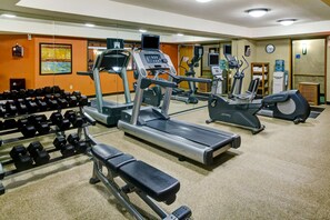 Ein Fitnessstudio mit Laufbändern, Crosstrainern und Hanteln.