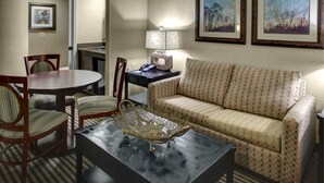 A living room with a round dining table, striped chairs, a patterned sofa, a coffee table with a decorative item, a lamp, and framed pictures on the wall. - Holiday Inn Express & Suites Atlanta Buckhead by IHG (Atlanta)