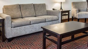 A living room with a grey sofa, a small table with a lamp, and a matching armchair. - Sleep Inn O'Fallon near I-64 (O'Fallon)