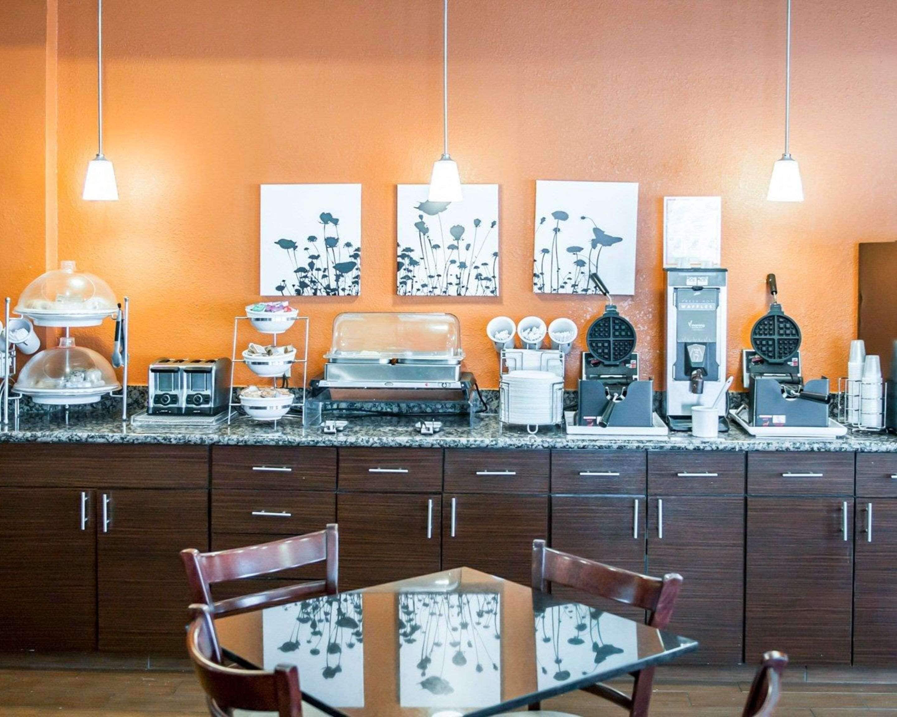 A kitchen with a buffet setup, including a waffle maker, coffee machine, and various food containers.