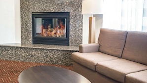 A living room with a fireplace, a sofa, a coffee table, and a lamp. - Sleep Inn O'Fallon near I-64 (O'Fallon)