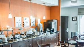 A modern kitchen with a central island, overhead pendant lights, and a dining area with wooden chairs and a table. - Sleep Inn O'Fallon near I-64 (O'Fallon)