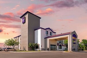 Un hotel con una torre destacada, un acceso cubierto y un estacionamiento.