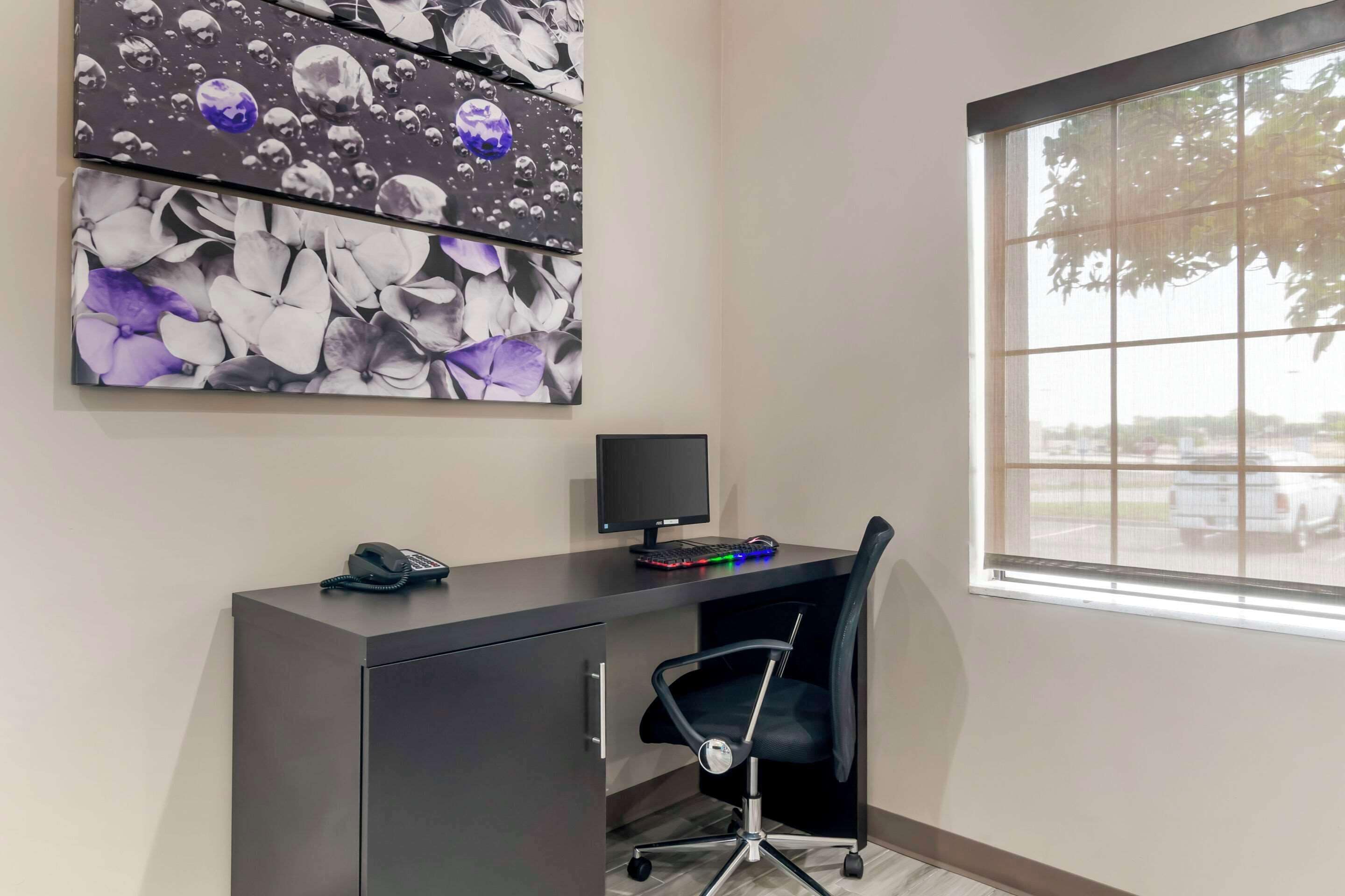 A modern office space with a desk, chair, computer, and a large window.