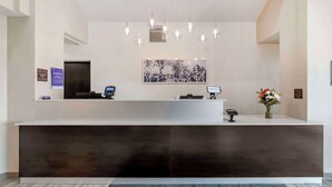 A reception desk with a modern design, a mounted artwork above it, and a digital screen.