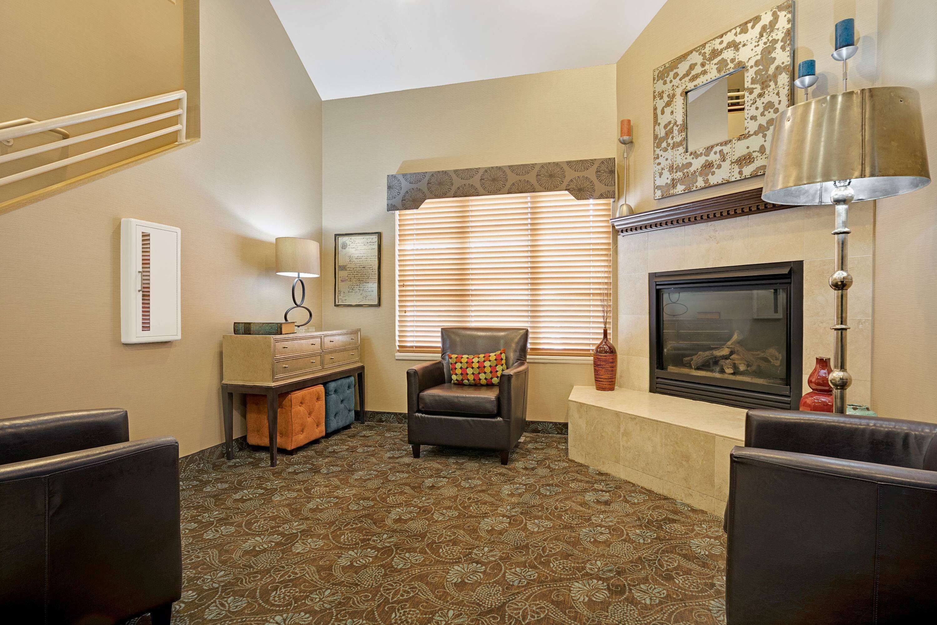 A living room with a fireplace, patterned carpet, and a comfortable seating area.