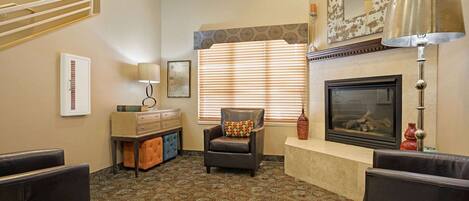 A living room with a fireplace, patterned carpet, and a comfortable seating area.