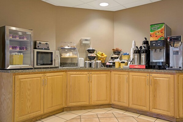 Una cocina equipada con microondas, tostadora, máquina de café y dispensador de zumo.