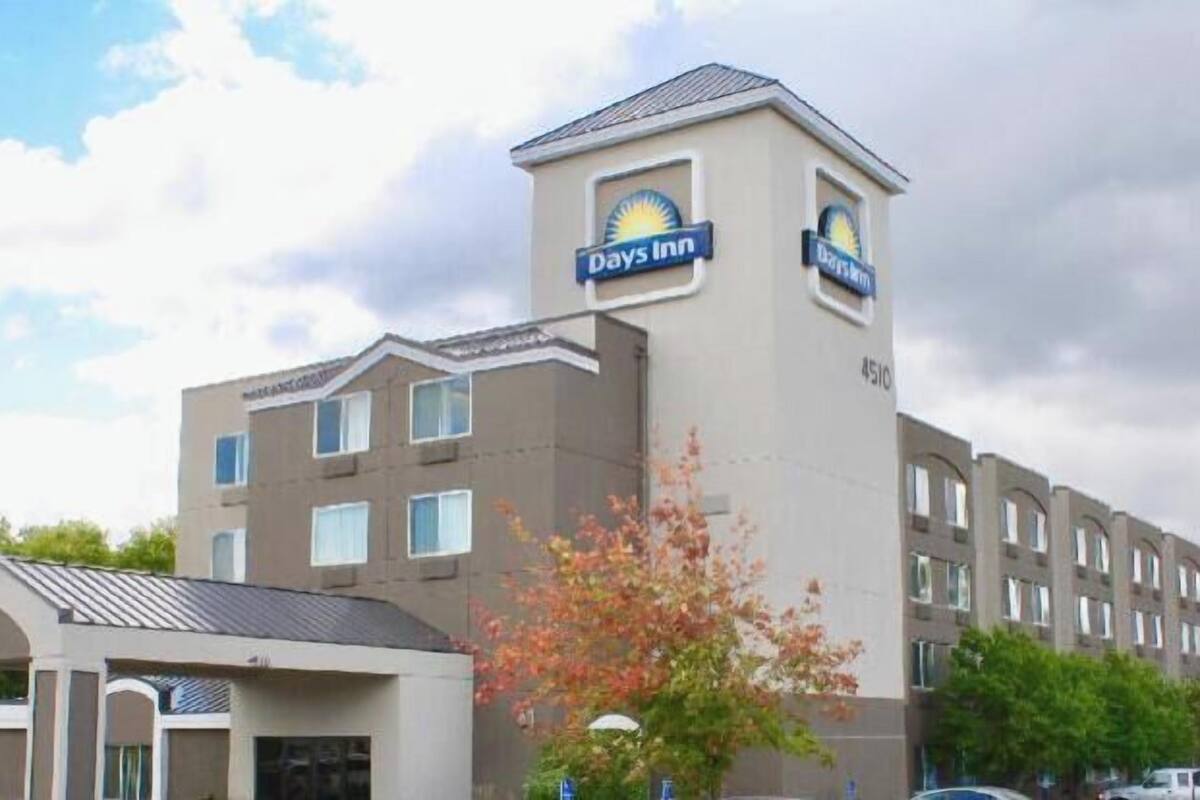 Un hotel Days Inn con una torre central, múltiples ventanas y un estacionamiento.