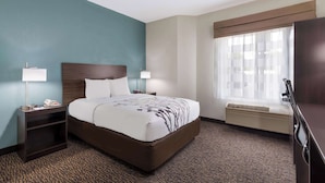 Een hotelkamer met een bed, nachtkastjes, een lamp, een verwarming en een raam met gordijnen.