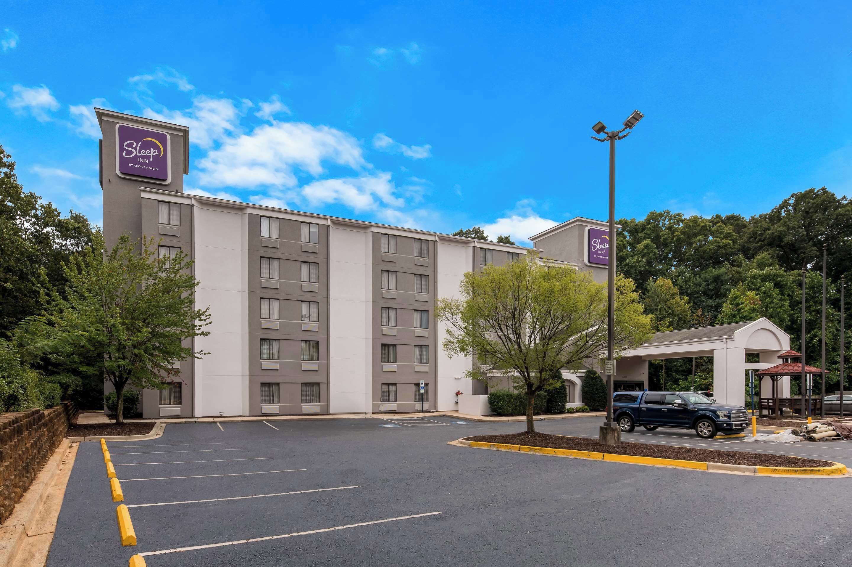 Um hotel Sleep Inn com estacionamento, entrada coberta e um edifício com vários andares.
