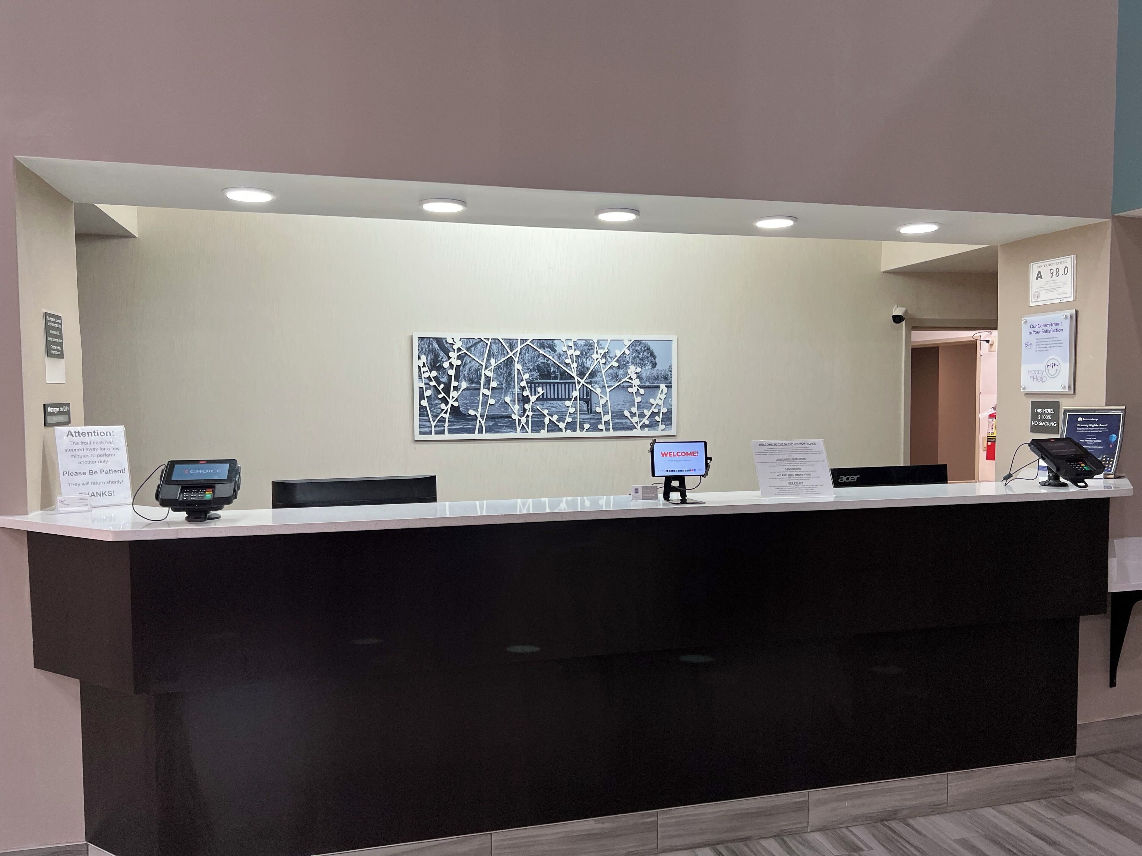 A hotel reception desk with a digital display, a cash register, and a sign indicating the room rate.