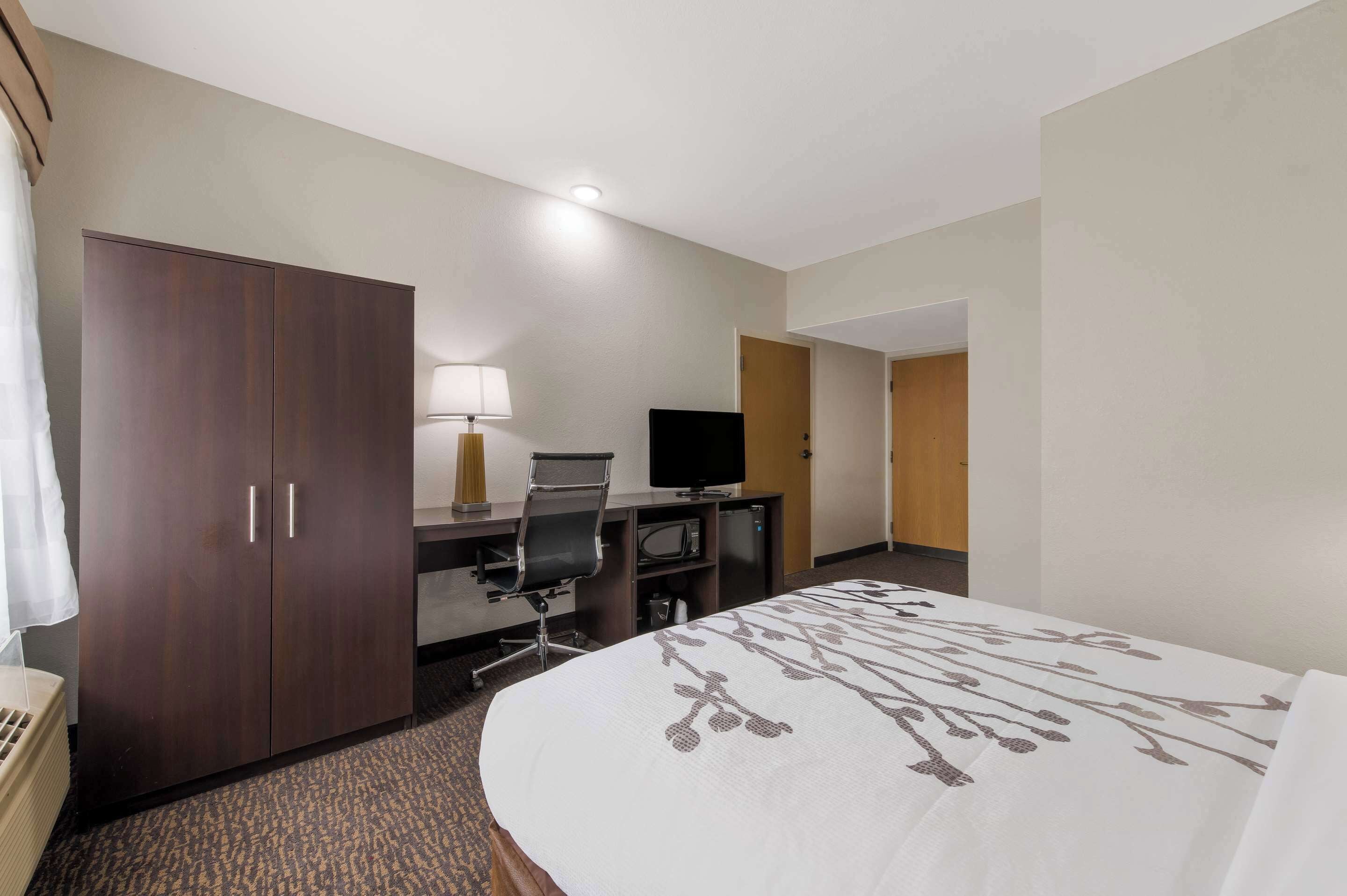 Une chambre d’hôtel comprenant un lit, un bureau avec un ordinateur, une télévision et une armoire.
