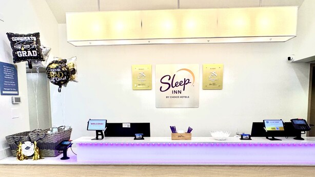 A reception desk with a 'Sleep Inn' sign, a 'Welcome!' sign, a 'Manager On Duty' sign, a 'Check Out' sign, and a 'Check In' sign. - Sleep Inn Staunton (Staunton)