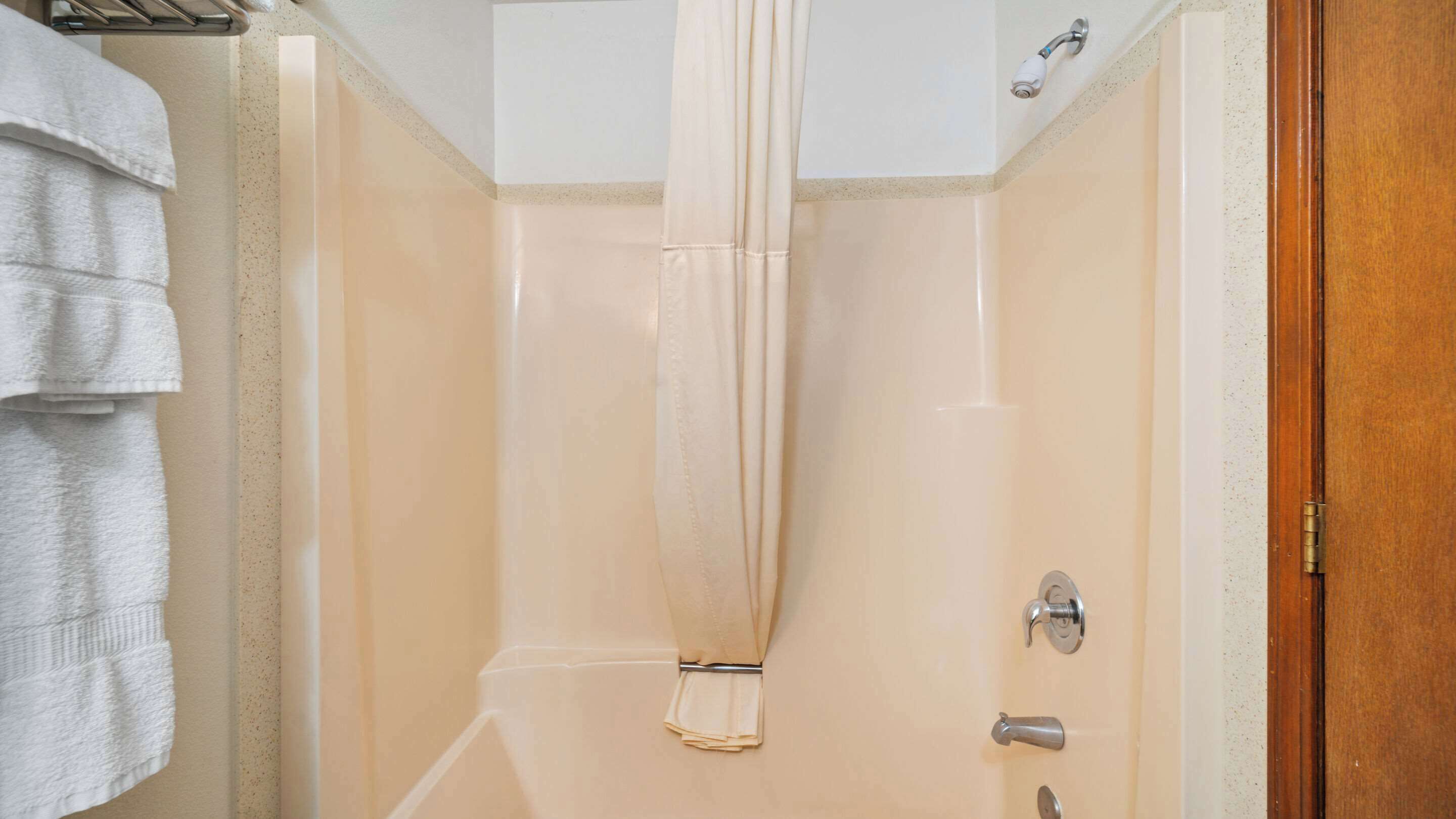 Une salle de bain avec un rideau de douche, un porte-serviettes et une porte dotée d’une poignée.