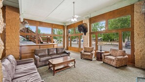 A spacious lobby with leather sofas, a wooden coffee table, and large windows offering views of the outdoors.