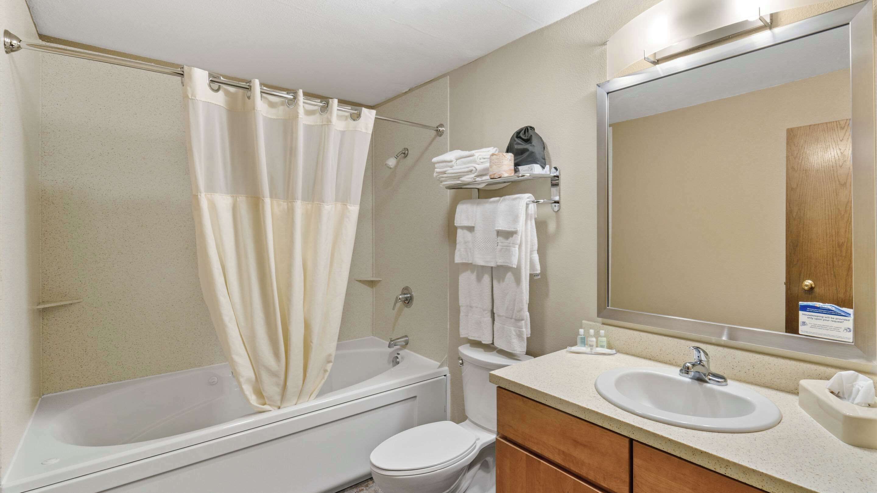 Un baño con bañera, inodoro, lavamanos y espejo.