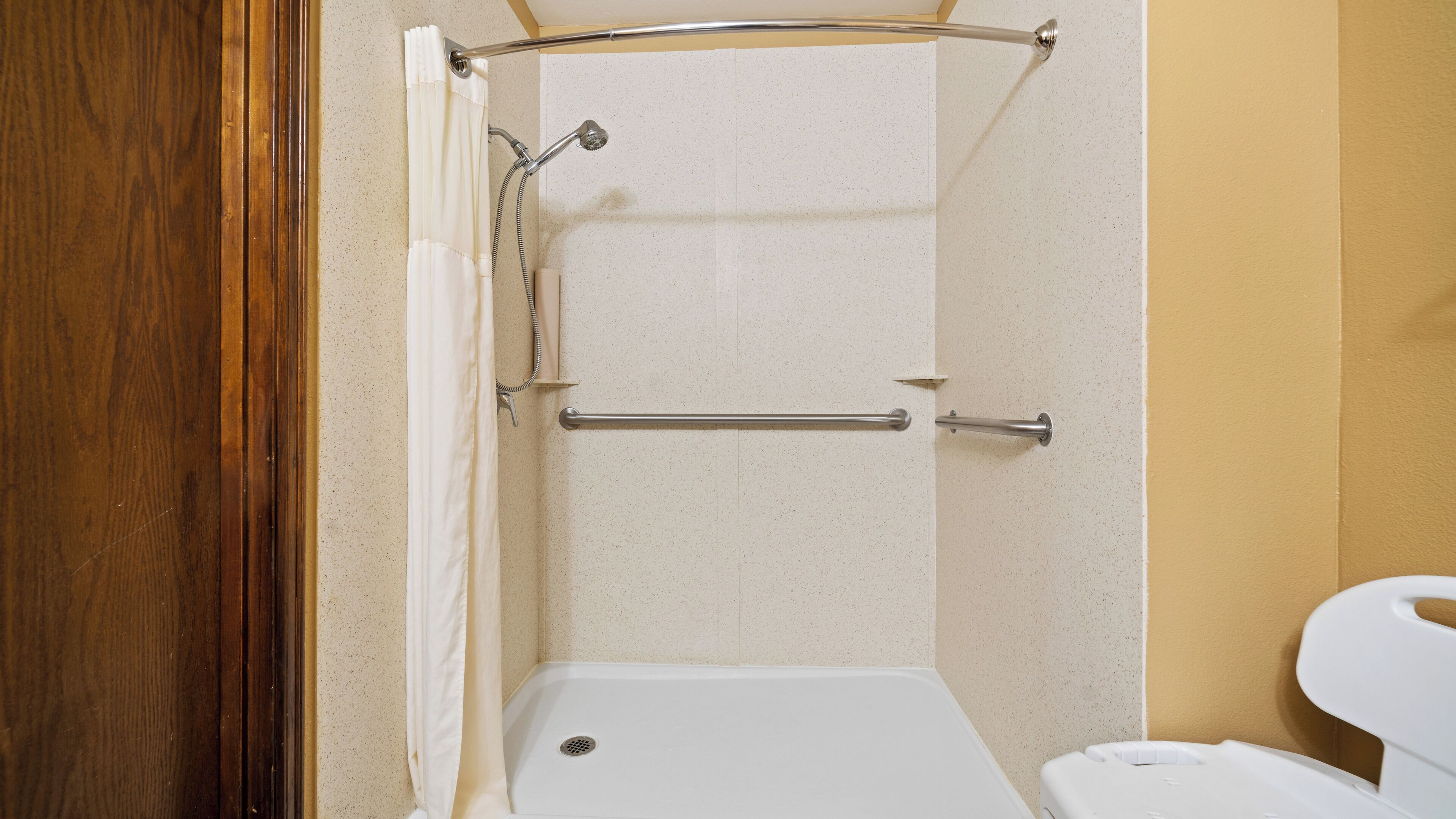 A bathroom with a shower, toilet, and grab bar.