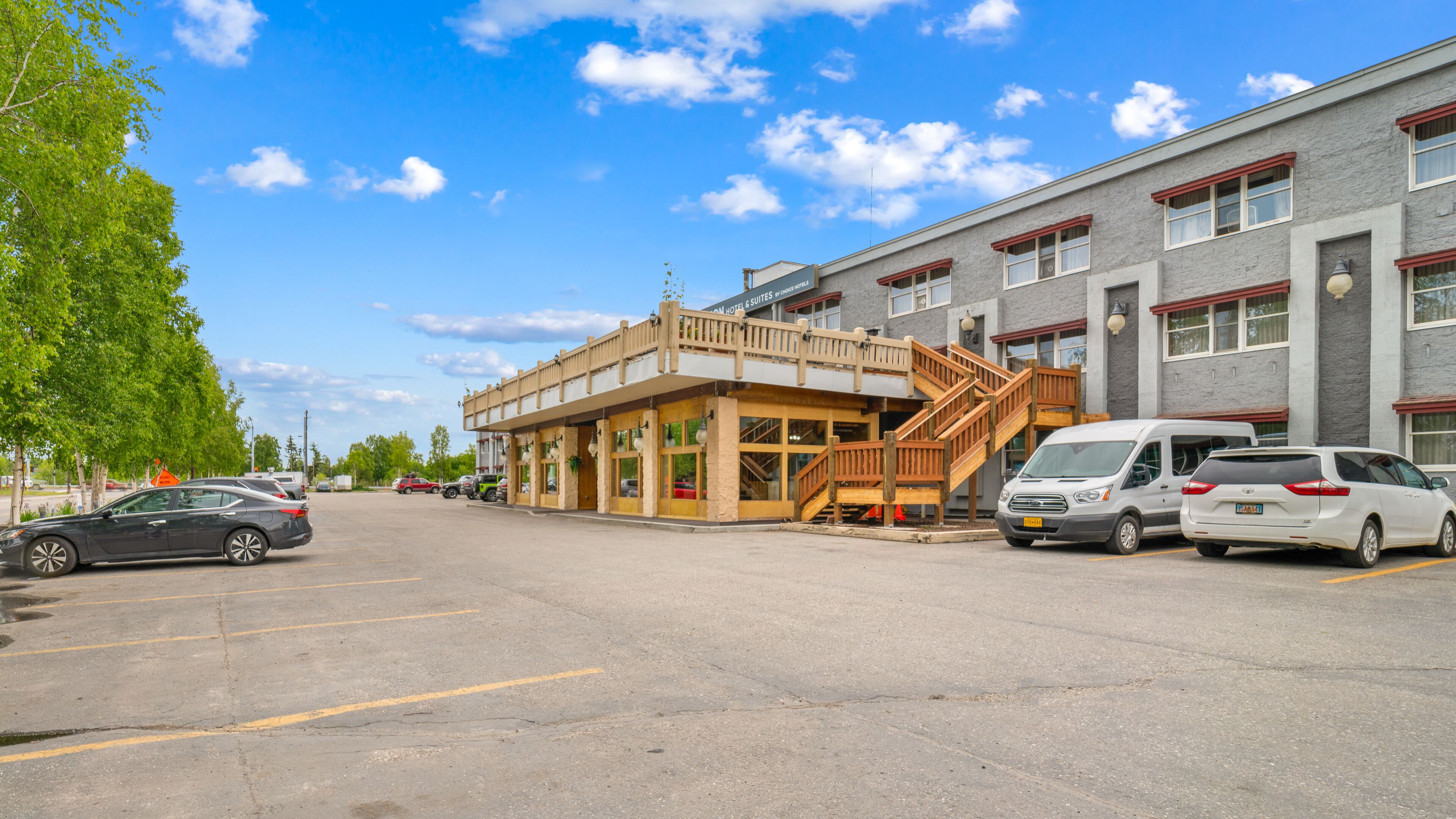 A hotel with a wooden facade, a staircase, and a parking lot with cars.
