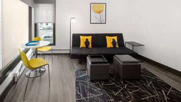 A modern room with a sofa, two yellow chairs, a small table, and a patterned rug.