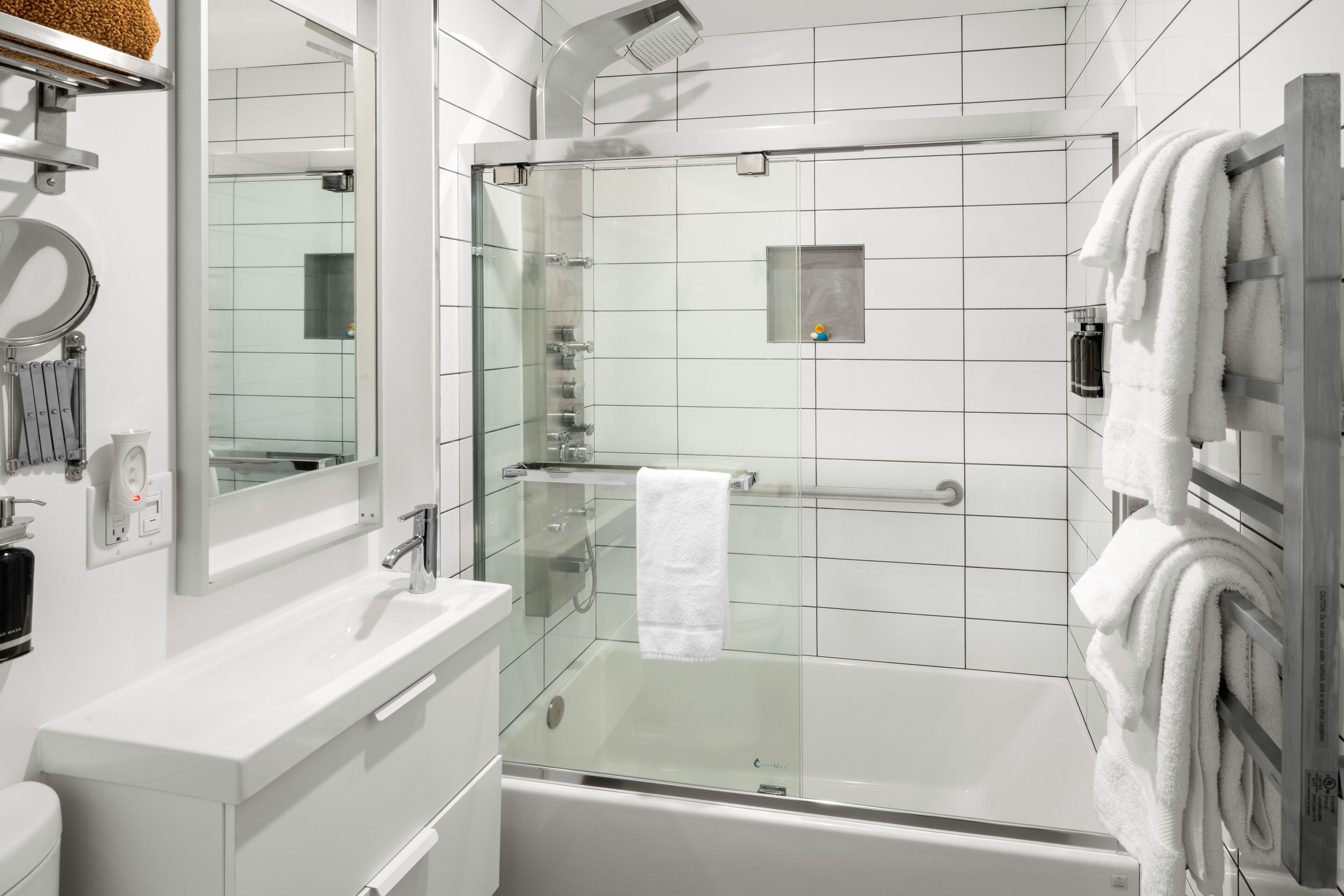 Une salle de bain moderne avec une douche à parois de verre, un lavabo blanc et un grand miroir.