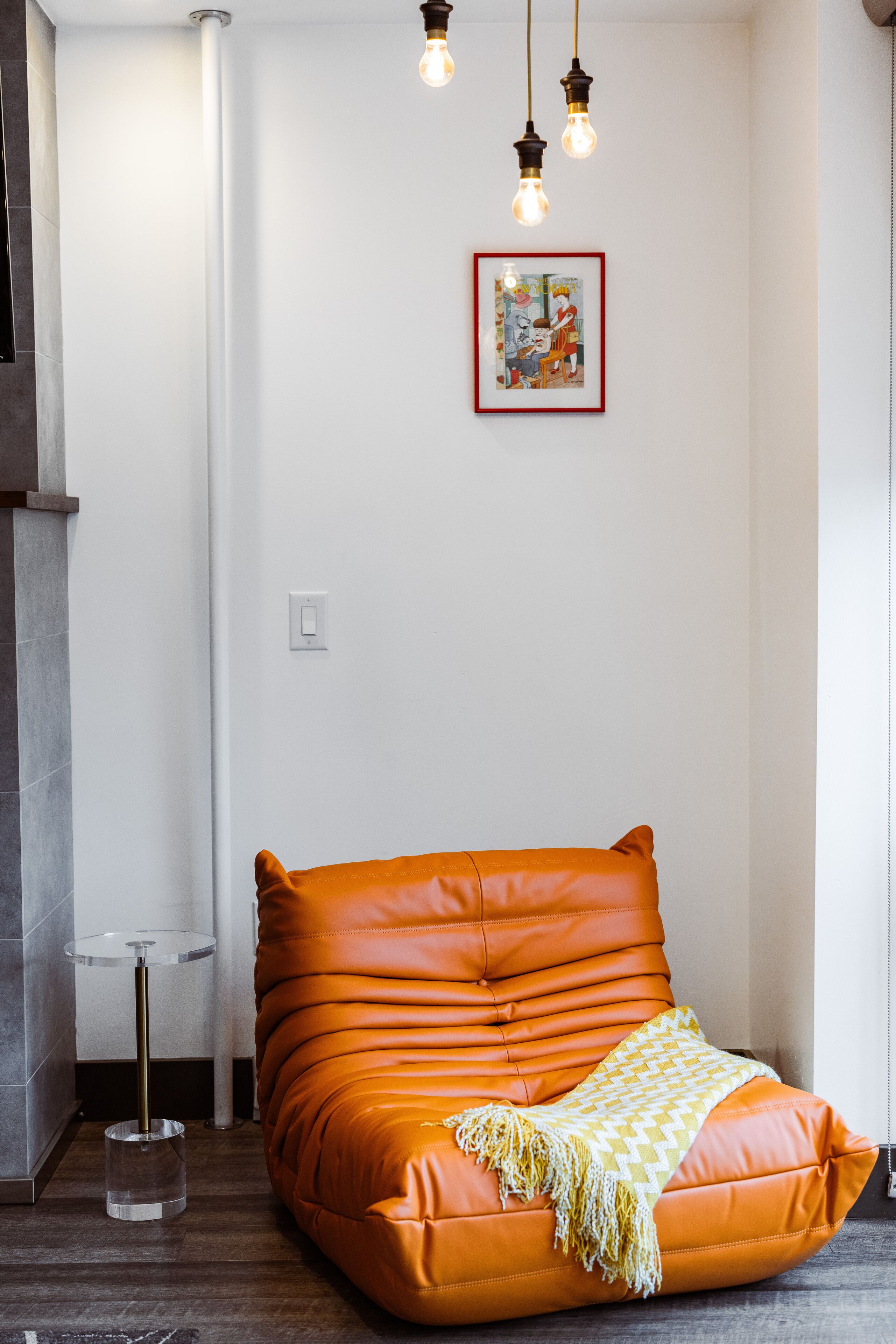 Una habitación moderna con un sofá de cuero, una mesita redonda y una obra de arte enmarcada en la pared.