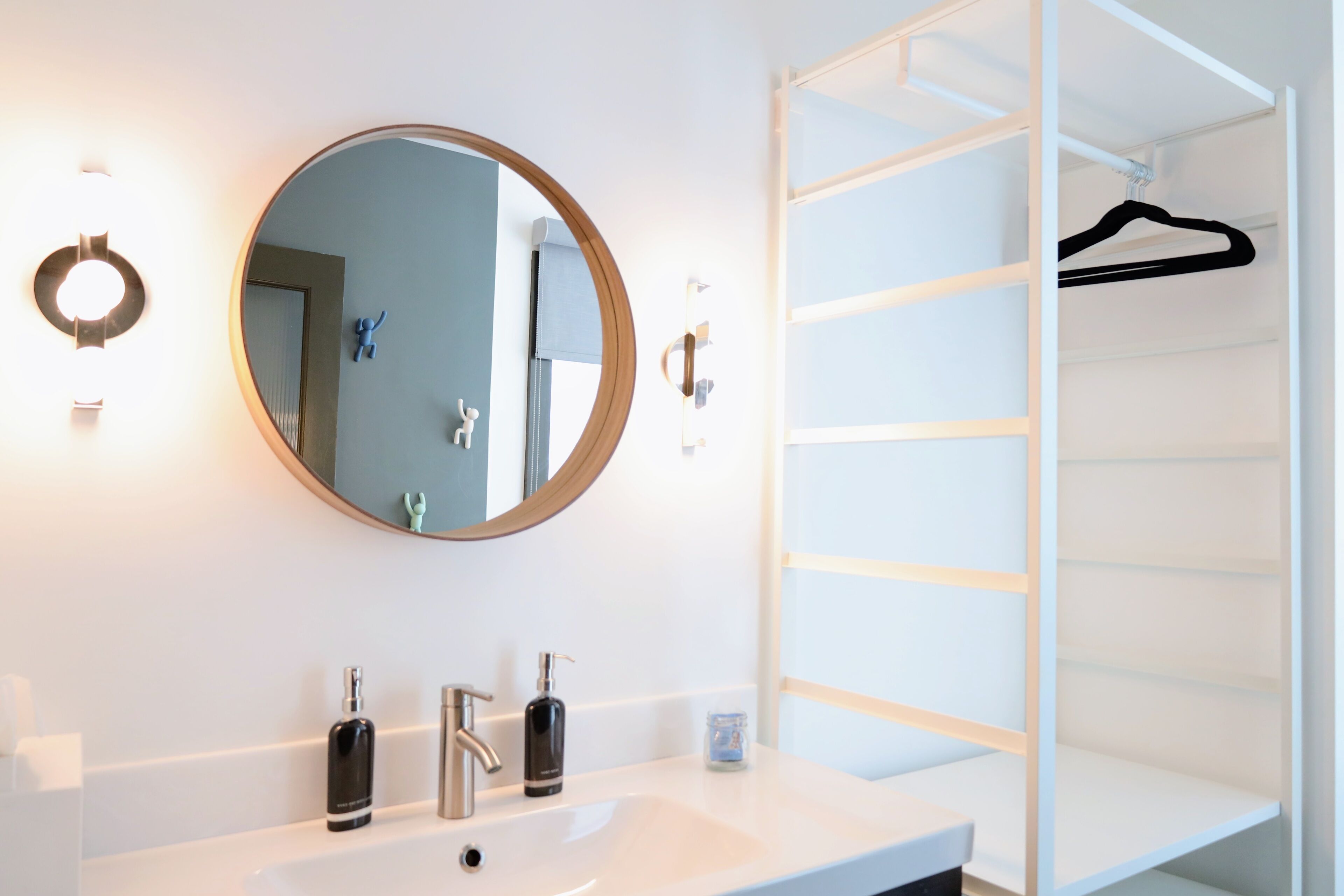 A bathroom with a round mirror, two sinks, and a white vanity.