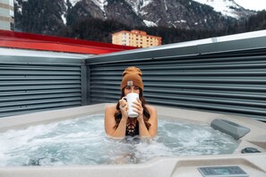 A person in a hot tub with a mountainous background.