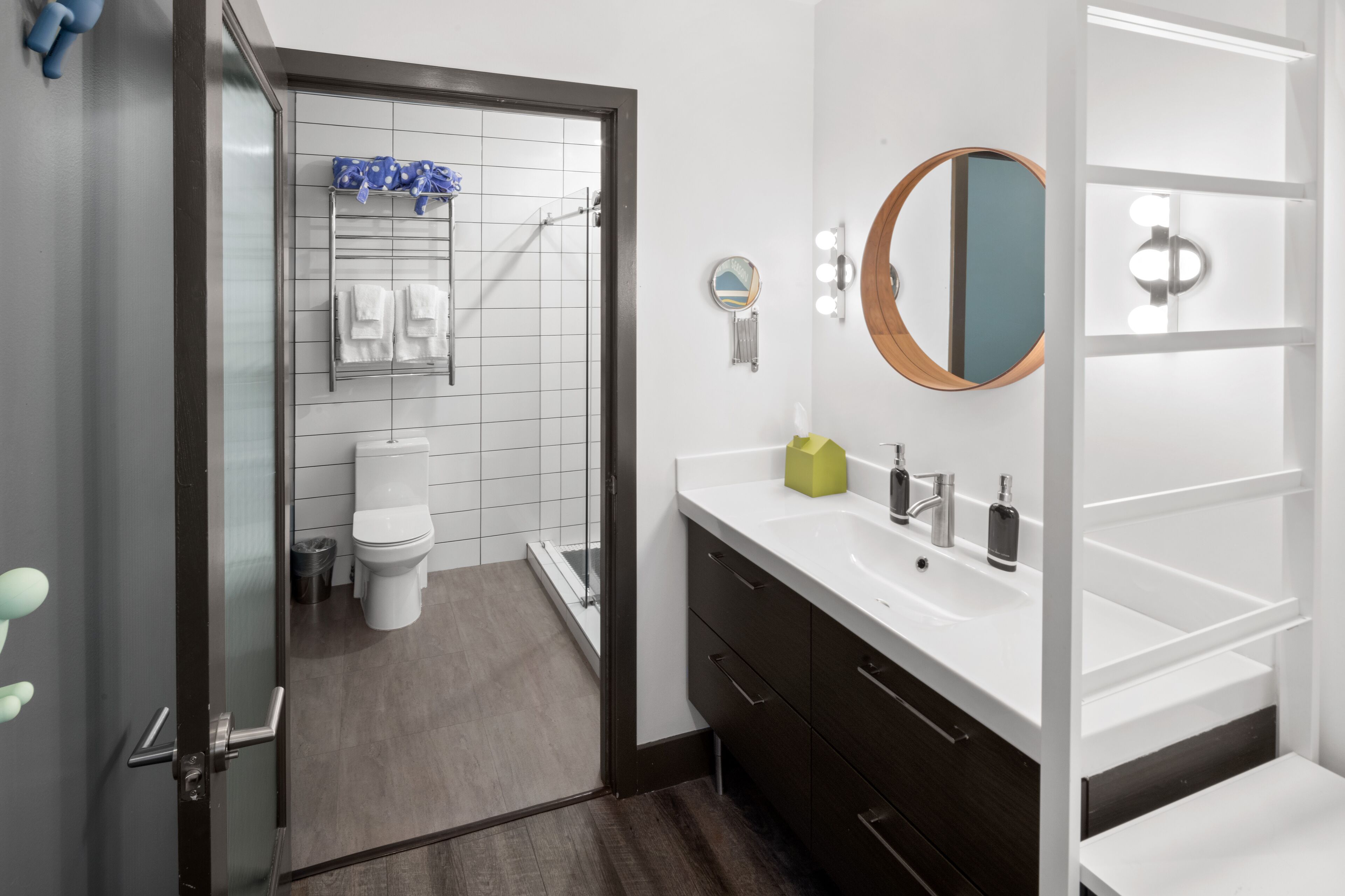 A modern bathroom with a glass shower enclosure, a white toilet, a vanity with a mirror, and a sink.