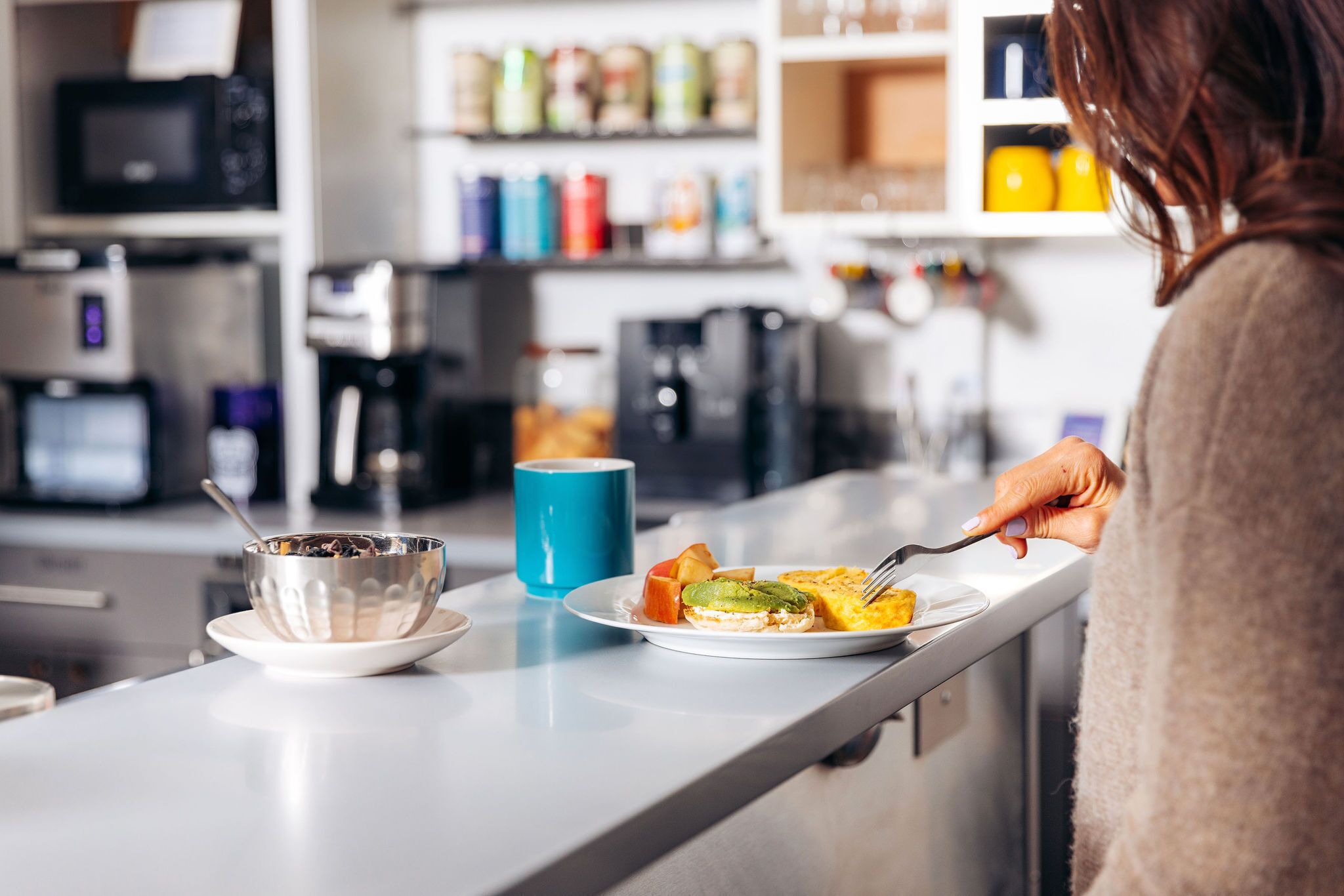 A kitchen counter with a bowl of cereal, a plate with toast and fruit, and a blue mug.