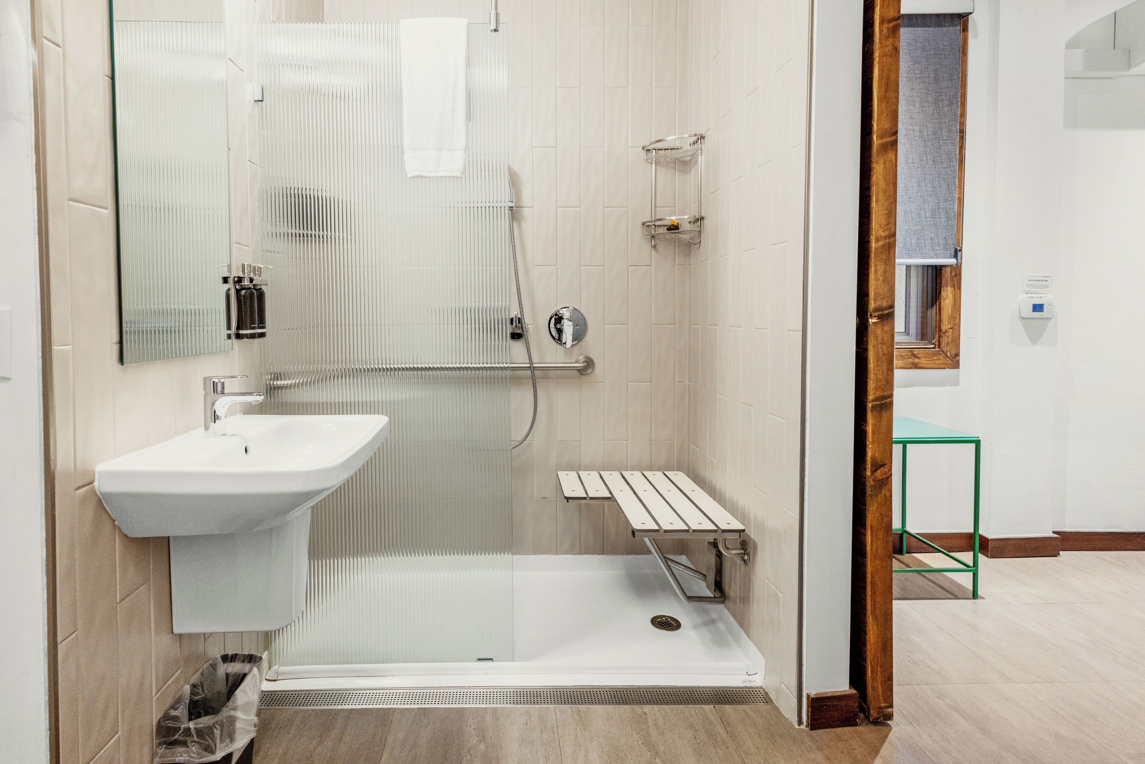 A modern bathroom with a glass shower enclosure, a white sink, and a small shelf.